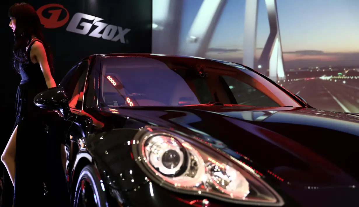 Seorang model berpose di dekat Porsche saat Tokyo Auto Salon 2017 di Chiba, Jepang, Jumat (13/1). Tokyo Auto Salon 2017 menghadirkan berbagai produk otomotif keluaran terbaru serta mobil-mobil kustom teranyar. (AFP PHOTO/ BEHROUZ MEHRI)
