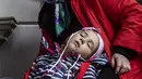 Seorang anak, Sofia tidur di sebelah neneknya Halina saat menunggu kereta mereka menuju Szczecin, di stasiun kereta api di Przemysl, Polandia tenggara, pada 5 April 2022. Lebih dari 4,2 juta pengungsi Ukraina telah meninggalkan negara itu sejak invasi Rusia, kata PBB. (Wojtek RADWANSKI / AFP)