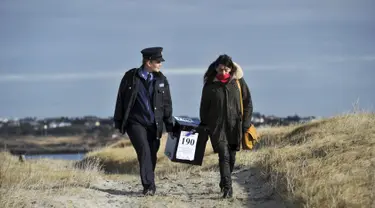 Polisi wanita Irlandia, Margaret Byrne dan pejabat ketua, Majella Harkin mengawal kotak suara ke pulau Innisfree, Irlandia, (25/2). Margaret seorang diri mengawal dan mengantarkan logistik pemilu ke pulau terpencil Irlandia. (REUTERS/Clodagh Kilcoyne)