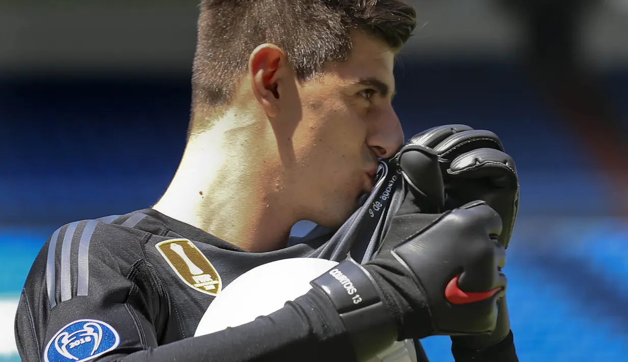 Kiper baru Real Madrid, Thibaut Courtois, mencium lambang klub saat diperkenalkan di Stadion Santiago Bernabeu, Madrid, Kamis (9/8/2018). Pemain berusia 26 tahun pindah setelah empat musim terakhir jadi kiper utama Chelsea. (AP/Andrea Comas)