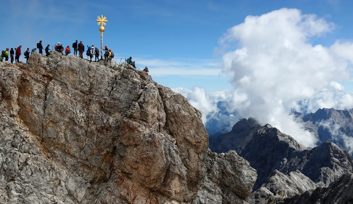 Orang-orang mengantre untuk mencapai puncak salib di puncak gunung tertinggi Jerman, Zugspitze, dekat Garmisch-Partenkirchen, Jerman pada 19 Agustus 2020. Setiap tahunnya gunung dengan ketinggian 2.962 meter tersebut membuat sekitar setengah juta pengunjung terpesona. (AP Photo/Matthias Schrader)