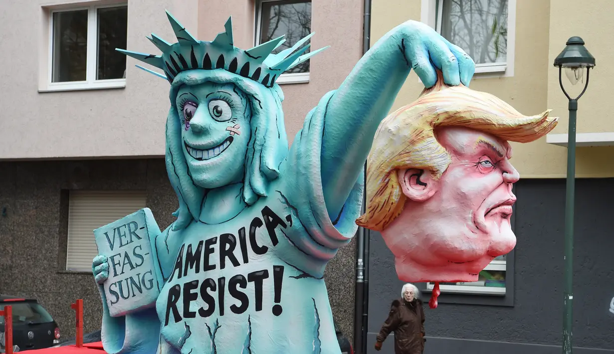 Sebuah patung berbentuk menyerupai Patung Liberty dan Presiden AS ikut dalam karnaval tradisional 'Rose Monday' di Dusseldorf, Jerman Barat, Senin (27/2). Karnaval 'Rose Monday' berisi sindiran satir para pemimpin dunia. (AFP PHOTO / Patrik STOLLARZ)