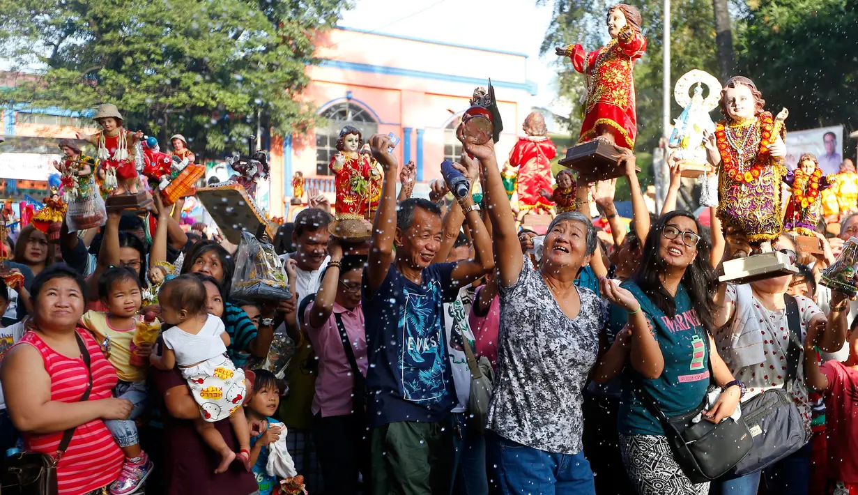 Sejumlah umat Katolik Roma mengangkat patung simbol Bayi Yesus saat pemberkatan di Manila, Filipina (21/1). Santo Nino adalah sebuah patung Yesus dalam bentuk seorang anak laki-laki kecil. (AP Photo / Bullit Marquez)