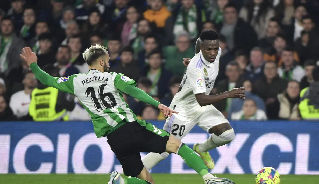 Bek Real Betis, German Pezzella (Kiri) berusaha merebut bola dari penyerang Real Madrid, Vinicius Junior selama pertandingan La Liga Spanyol di stadion Benito Villamarin di Seville, Senin (6/3/2023). Real Madrid bermain imbang dengan Real Betis dengan skor 0-0. (AFP/CRISTINA QUICLER)