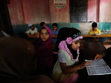 Seorang anak perempuan Kashmir saat membaca Al-Quran di sebuah madrasah lokal selama bulan Ramadan di Srinagar, Kashmir yang dikuasai India, (30/5). Umat muslim di seluruh dunia saat ini tengah menjalani ibadah puasa. (AP Photo / Mukhtar Khan)