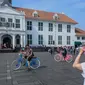 Wisatawan berfoto dengan latar belakang Museum Fatahillah di kawasan Kota Tua, Jakarta, Sabtu (8/6/2019). Selama libur lebaran 2019, jam berkunjung ke berbagai museum di kawasan wisata sejarah Kota Tua diperpanjang hingga pukul 20.00 WIB. (Liputan6.com/Faizal Fanani)