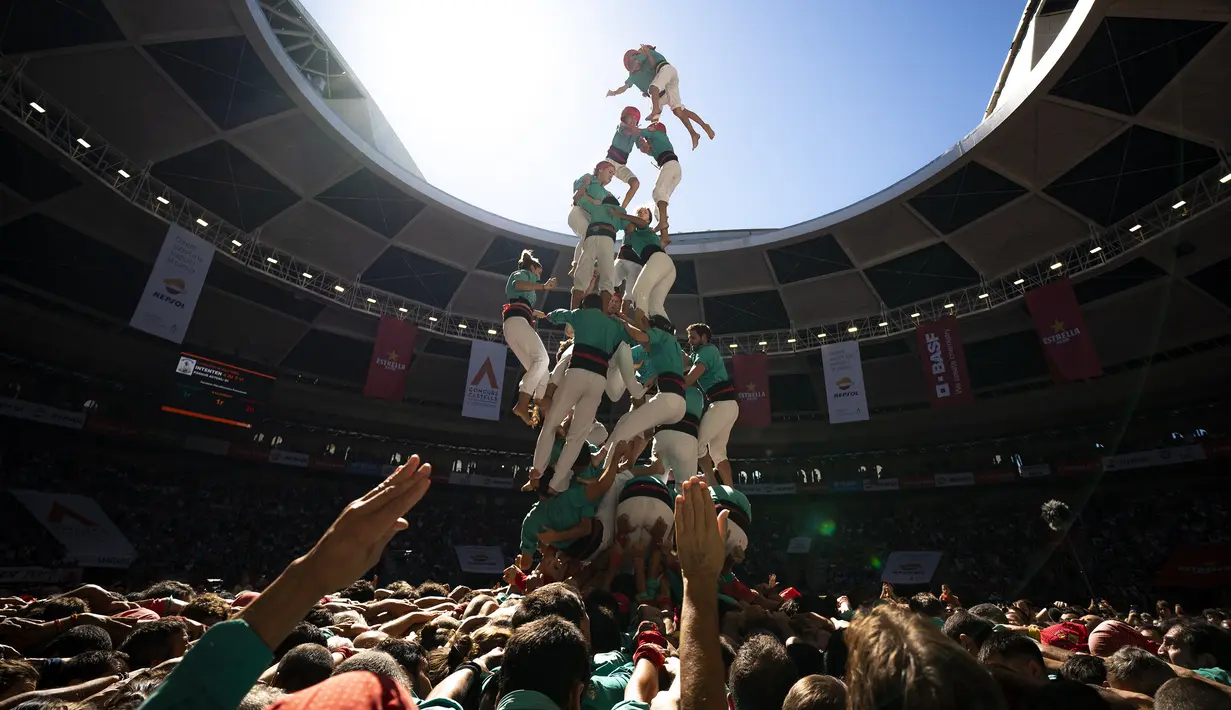 Anggota "Castellers de Vilafranca" jatuh setelah menyelesaikan menara manusia mereka  selama Kompetisi Menara Manusia ke-28 di Tarragona, Spanyol, Minggu (2/10/2022). Tradisi ini telah masuk sebagai warisan budaya dunia yang di catat oleh UNESCO sejak 2010. (AP Photo/Joan Mateu Parra)
