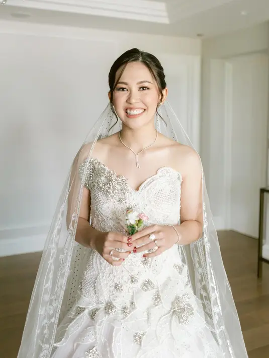 Gaun ini menampilkan aksen lace yang lembut dan detail bunga beads yang indah. Potongan off-shoulder pada gaunnya menciptakan tampilan klasik nan menawan yang sangat cocok untuk seorang mempelai wanita. [@ribkasugiarto].