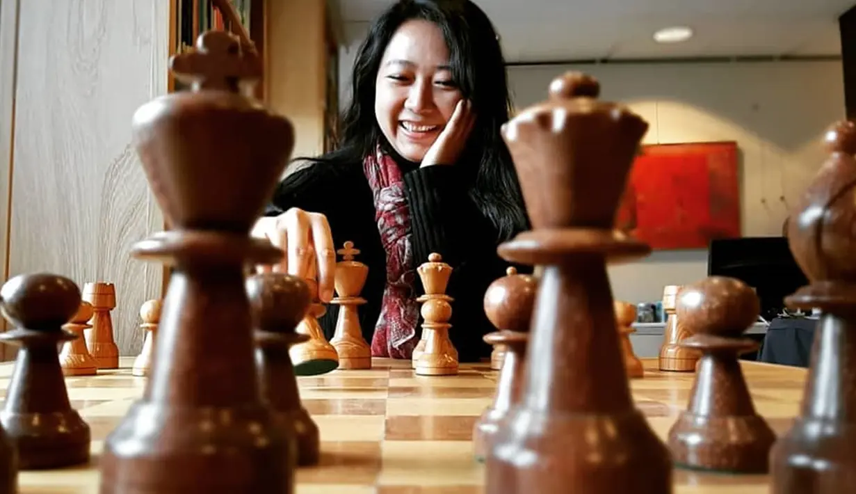 Perempuan berusia 28 tahun ini tidak hanya penuh konsentrasi saat bertanding catur, namun beberapa momen ia juga melemparkan senyum manis. Gayanya Irene Sukandar saat bermain catur pun selalu mencuri perhatian publik. (Liputan6.com/IG/@irene_sukandar)