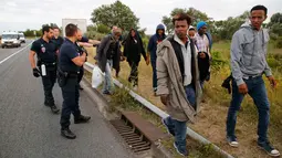 Petugas berusaha mengusir para imigran yang berusaha memasuki kawasan Channel Tunnel di Frethun, Calais, Perancis (3/8/2015). Pada malam hari imigran masuk keterowongan rel bawah laut yang menghubungkan Perancis dan Inggris. (REUTERS/Pascal Rossignol)