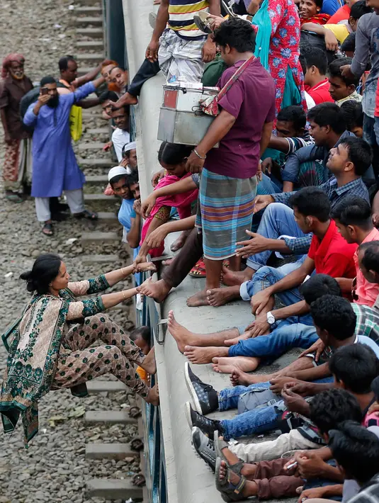 Seorang wanita berusaha naik ke atap kereta api saat akan pulang kampung di stasiun kereta api di Dhaka, Bangladesh, (22/6). Ribuan yang bekerja di Dhaka pulang ke kampung halamannya untuk merayakan lebaran bersama keluarganya. (AP Photo/A.M.Ahad)