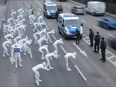 Aktivis dari Greenpeace mengenakan pakaian serba putih turun ke jalan melakukan aksi di Stuttgart, Jerman (19/2). Mereka melakukan aksi memprotes polusi yang diakibatkan oleh knalpot mobil diesel. (Sebastian Gollnow/dpa/AFP)