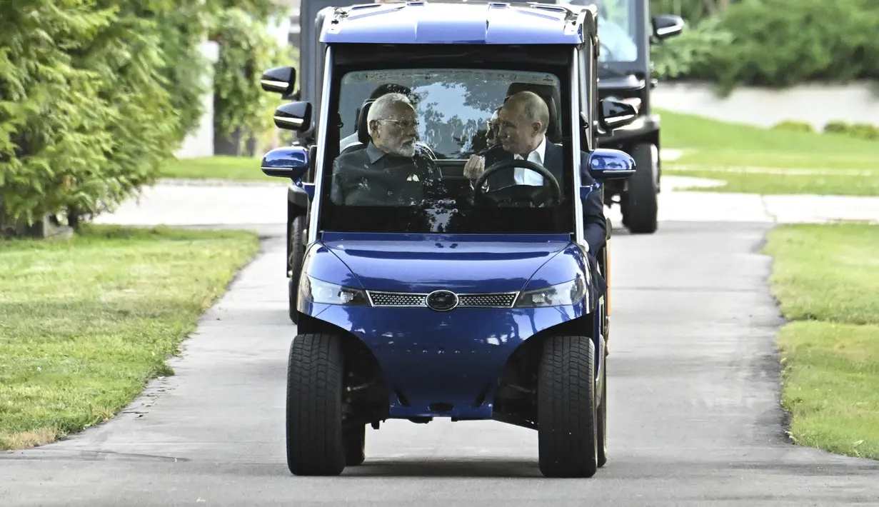Putin mengantar Modi berkeliling dengan kereta golf. (Sergei Bobylev, Sputnik, Kremlin Pool Photo via AP)