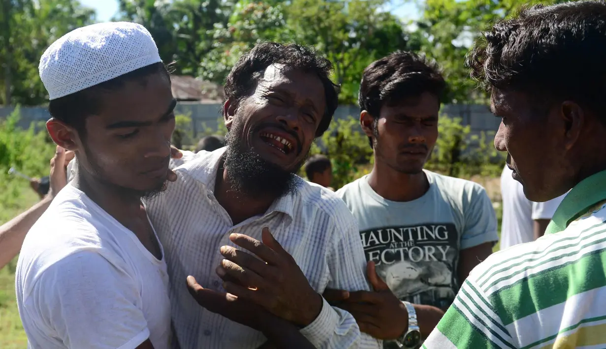 Alif Jukhar (kedua kiri) menangis setelah menguburkan kedua orang tuanya di pemakaman di Sha Porir Dwip, Teknaf (9/10). Alif Jukhar, yang telah lama tinggal di Bangladesh, kehilangan sembilan saudara termasuk ibu dan ayahnya. (AFP Photo/Munir Uz Zaman)