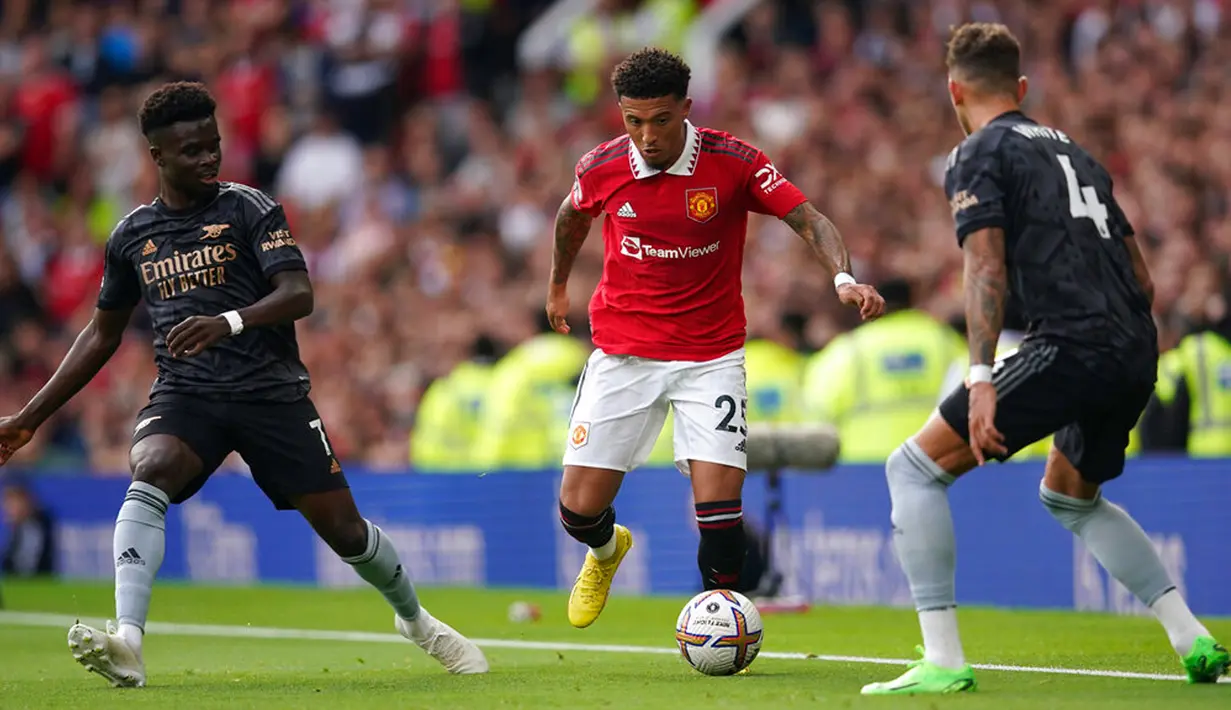 Pemain Manchester United Jadon Sancho (tengah) mengontrol bola di depan pemain Arsenal Ben White (kanan) dan Bukayo Saka pada pertandingan sepak bola Liga Premier Inggris di Stadion Old Trafford, Manchester, Inggris, 4 September 2022. Manchester United menang atas Arsenal dengan skor 3-1. (AP Photo/Dave Thompson)