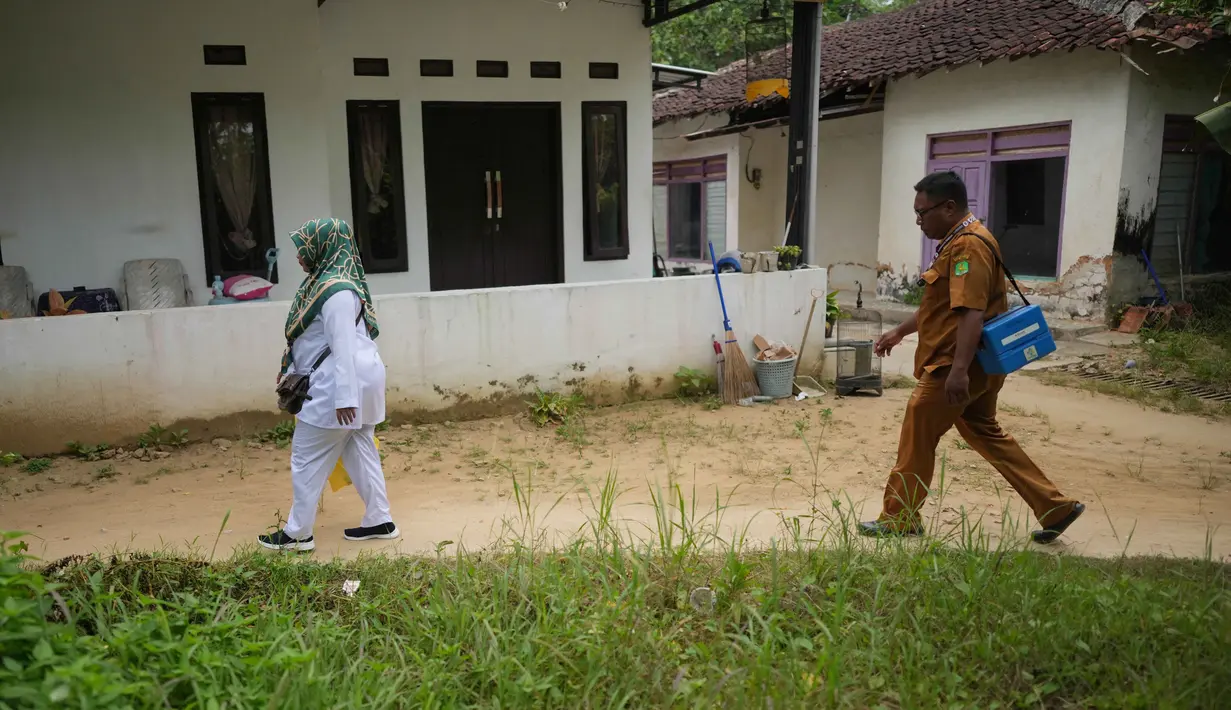 Tidak sendiri, Siti Nurjanah bersama rekan-rekannya rela menyusuri permukiman warga untuk memberikan vaksinasi campak kepada anak-anak yang telah terdaftar. (AP Photo/Dita Alangkara)