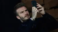 David Beckham mengambil gambar saat menonton pertandingan antara PSG dan Real Madrid di stadion Parc des Princes di Paris (6/3). David Beckham, yang pernah berkostum Madrid dan PSG juga turut hadir menonton pertandingan. (AP Photo/Christophe Ena)