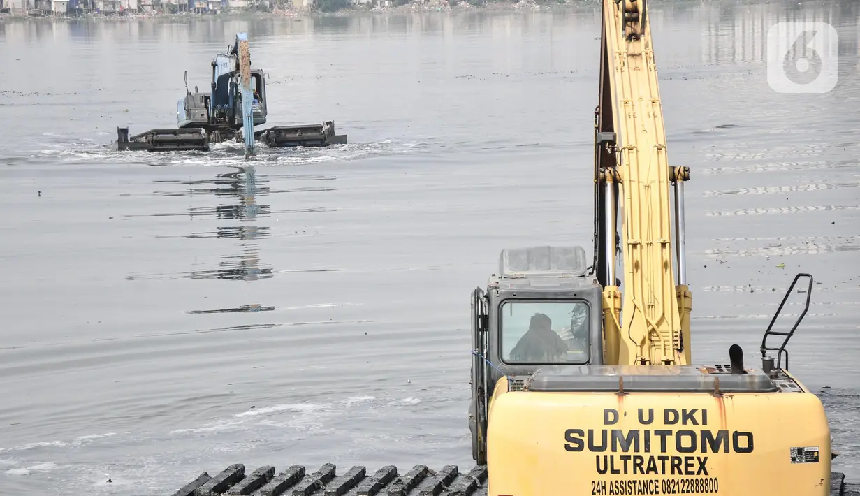 Pekerja menggunakan beko mengeruk lumpur yang mengendap di Waduk Pluit, Senin (13/6/2022). Pengerukan lumpur rutin ini dilakukan sebagai upaya mengurangi endapan serta tanaman liar dan mencegah banjir di kawasan tersebut. (merdeka.com/Iqbal S Nugroho)