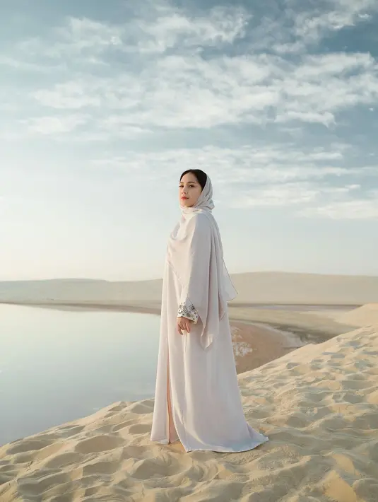 Cantiknya Nagita Slavina di tengah padang pasir menggunakan kaftan dan kerudung putih yang menutupi kepalanya. Gayanya bak princess Arab. [Foto: Instagram/raffinagita1717]