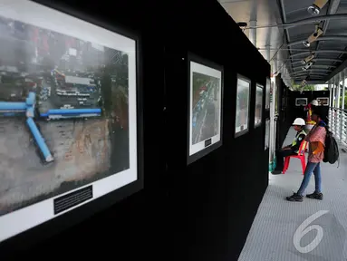 Pengunjung mengamati pameran foto jurnalis 'Satu Tahun Groundbreaking MRT di JPO Bundaran HI, Jakarta, Jumat (31/10/14). (Liputan6.com/Johan Tallo)