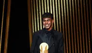 Penyerang muda Barcelona, Lamine Yamal, menerima Kopa Trophy, lambang pemenang predikat pemain muda terbaik di seremonial Ballon d'Or yang berlangsung di Theatre du Chatelet di Paris, Senin (28/10/2024) malam waktu setempat. (FRANCK FIFE / AFP)