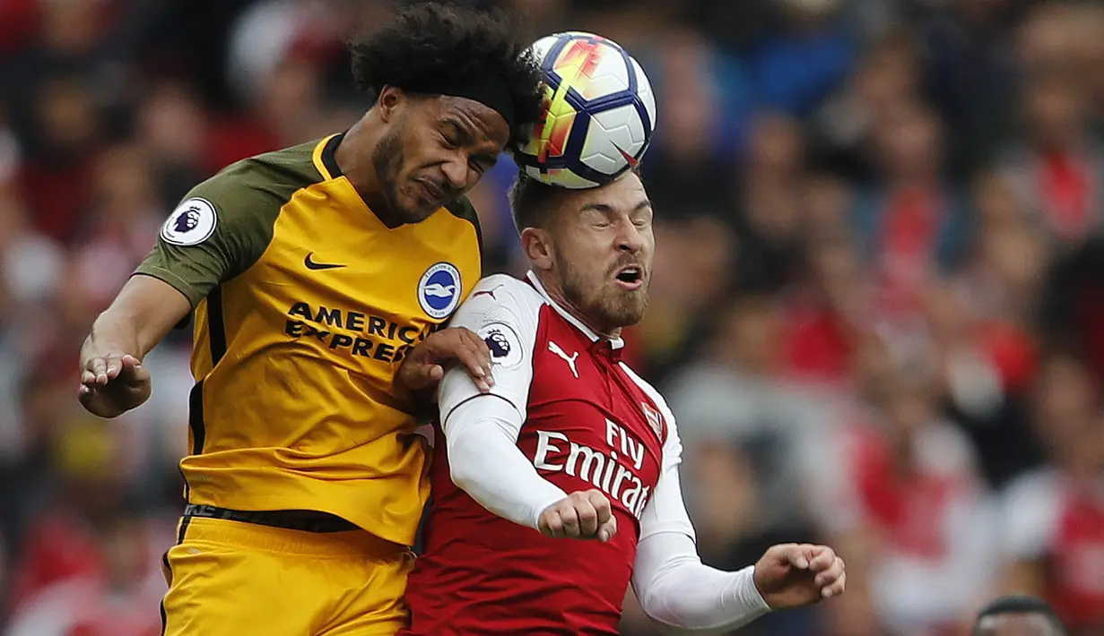 Duel pemain Brighton, Gaetan Bong (kiri) dengan pemain Arsenal, Aaron Ramsey pada lanjutan Premier League di Emirates Stadium, London, (1/10/2017). Arsenal menang 2-0. (AP/Frank Augstein)