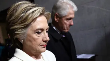 Mantan calon presiden dari partai Demokrat, Hillary Clinton berjalan dengan suaminya, Bill Clinton untuk menghadiri upacara pelantikan Donald Trump menjadi Presiden AS ke-45 di Washington, DC, AS, (20/1). (Win McNamee/Pool Photo via AP)