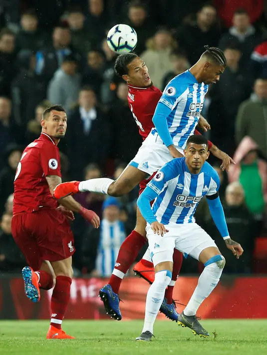 Duel udara bek tengah Liverpool, Virgil van Dijk dengan pemain Huddersfield Town, Juninho Bacuna dalam laga lanjutan Premier League 2018-19 pekan ke-36 di Anfield, Jumat (26/4). Bermain di kandang sendiri, Liverpool menang dengan skor telak 5-0.  (REUTERS/Andrew Yates)