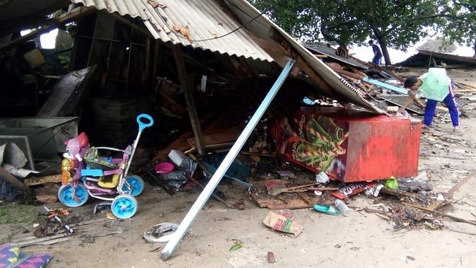 Seorang pria mencari barang-barang dari rumahnya yang rusak setelah tsunami menerjang Pantai Carita, di perairan Banten, Minggu (23/12). Data sementara jumlah korban dari bencana tsunami di Selat Sunda tercatat 43 orang meninggal dunia. (SEMI / AFP)