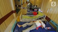 Pasien covid-19 saat perawatan pasien khusus virus corona pada lorong UGD di RSUD Kota Bekasi, Jumat (25/06/2021). Puluhan pasien covid-19 saat ini dirawat dalam tenda darurat karena keterisian tempat tidur yang penuh akibat lonjakan kasus. (merdeka.com/Arie Basuki)