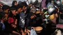 Warga Palestina menunggu bantuan gula dan beras di dapur umum di Khan Younis, Jalur Gaza selatan, Jumat, 31 Oktober 2025. Mereka datang dengan membawa panci dan piring kosong serta harapan mendapat bantuan makanan. (AP Photo/Abdel Kareem Hana)