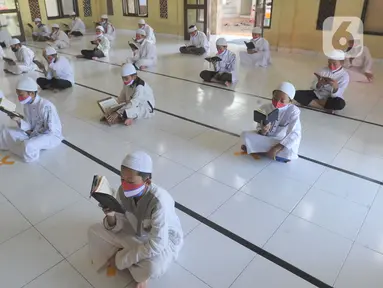 Sejumlah santri berusia belasan tahun membaca Al quran atau tadarus bersama-sama dengan menerapkan jaga jarak di Masjid Daarul Qu'ran Pesantren Al Kautsar, Cibinong, Bogor, Kamis (7/5/2020). Kegiatan Khatam Al quran tersebut dilakukan rutin di setiap bulan Ramadan. (merdeka.com/Arie Basuki)