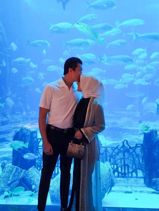 Makin romantis, momen Reino mengecup kening sang istri saat diner. Dalam video singkatnya, keduanya tampak berjalan bergandengan tangan menyasikan ikan di aquarium besar.  "Under Water Dinner," tulis Syahrini. [Instagram/princessyahrini]