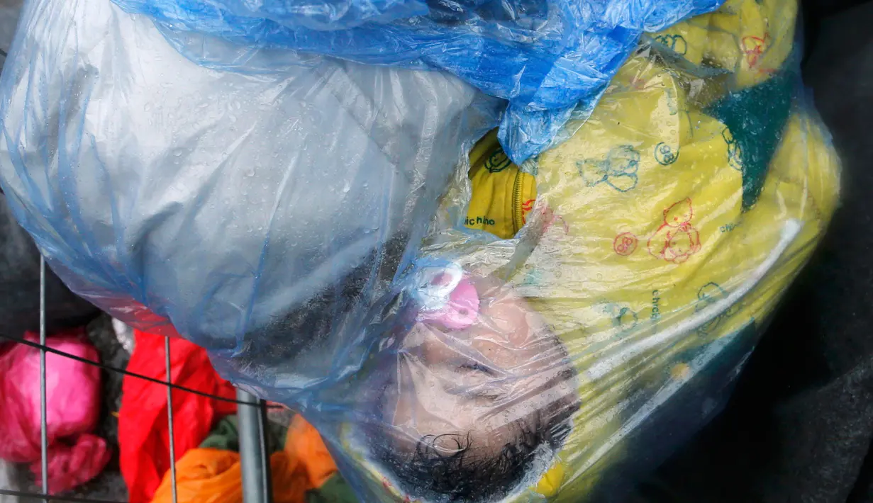 Anak pengungsi tidur dalam perjalanan dari Slovenia melintasi perbatasan menuju Trnovec, Kroasia, Senin (19/10). Ribuan orang terjebak cuaca dingin di desa perbatasan Serbia Berkasovo setelah Kroasia membendung para pendatang. (REUTERS/Antonio Bronic)