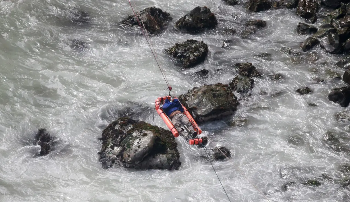 Seorang pria dievakuasi dengan menyeberangi sungai setelah sebuah bus jatuh dari tebing di Pasamayo, Peru, Selasa (3/1). Bus  yang membawa sekitar 53 penumpang tersebut jatuh ke dalam jurang setinggi 100 meter. (Vidal Tarky, Andina News Agency via AP)