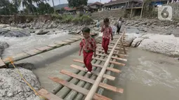 Siswa melintasi jembatan darurat berbahan bambu di Kampung Ciasahan, Desa Sukamaju, Kabupaten Bogor, Kamis (6/2/2020). Pembangunan kembali jembatan Ciasahan yang ambruk akibat banjir bandang pada Rabu (1/1) itu diharapkan mampu memulihkan aktivitas dan perekonomian warga. (merdeka.com/Arie Basuki)