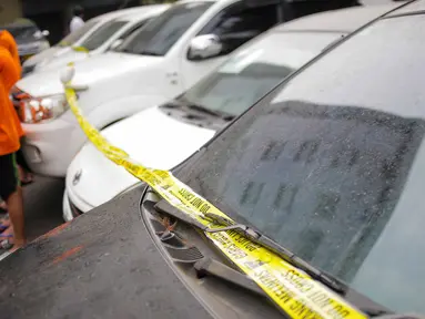 Petugas memasang garis polisi pada puluhan barang bukti mobil yang berhasil disita saat gelar kasus di Polda Metro Jaya, Rabu (18/9/2019). Subdit 6 Ditreskrimum PMJ mengungkap kejahatan penggelapan mobil dengan barang bukti 28 kendaraan roda empat dan sejumlah tersangka. (Liputan6.com/Faizal Fanani)