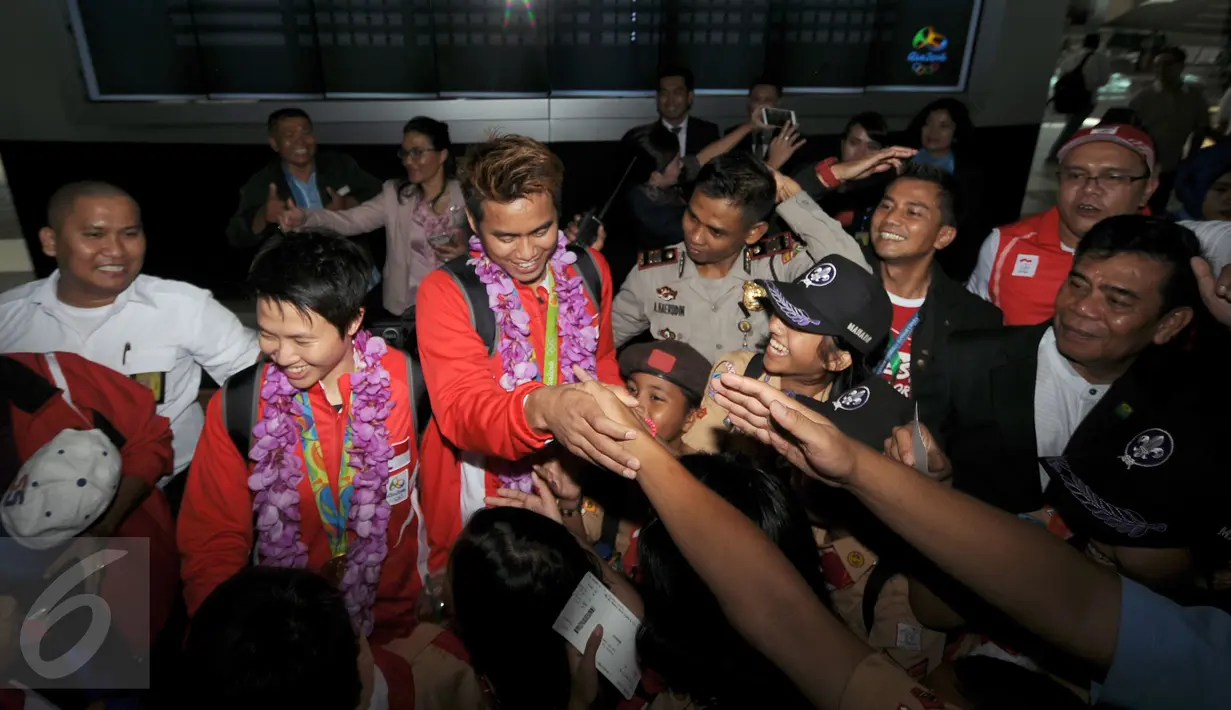 Sejumlah orang berusaha bersalaman dengan Lilyana NatsirdanTontowi Ahmad usai tiba di Bandara Soekarno Hatta, Banten, Selasa (23/8/2016). Tontowi Ahmad/Lilyana Natsir berhasil meraih emas olimpiade Rio 2016 di Brasil. (Liputan6.com/HelmiFithriansyah)