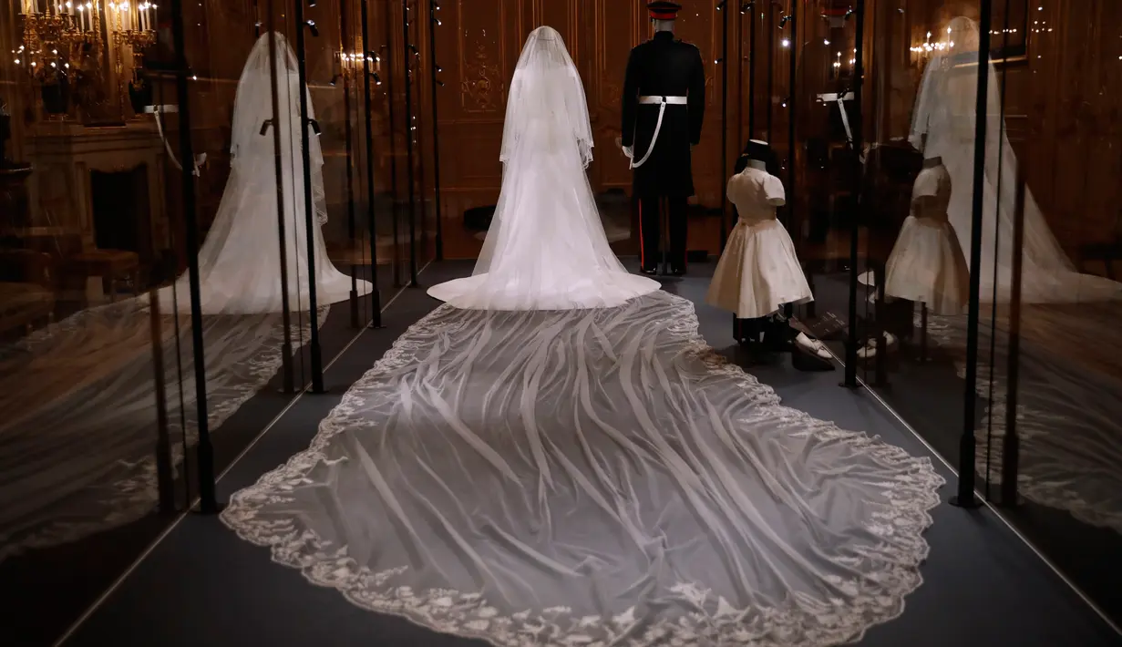 Gaun pernikahan Meghan Markle dan Pangeran Harry ditampilkan pada pameran A Royal Wedding di Kastil Windsor, London, 25 Oktober 2018. Gaun yang dikenakan Meghan, dipajang di kotak kaca besar di samping kostum pernikahan Pangeran Harry. (AP/Matt Dunham)