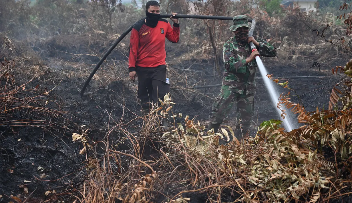 Prajurit TNI dan petugas Badan Penanggulangan Bencana Daerah (BPBD) berusaha memadamkan kebakaran hutan dan lahan di Kabupaten Kampar, Provinsi Riau (12/9/2019). Titik api kebakaran yang terjadi di Indonesia telah melonjak tajam. (AFP Photo/Adek Berry)