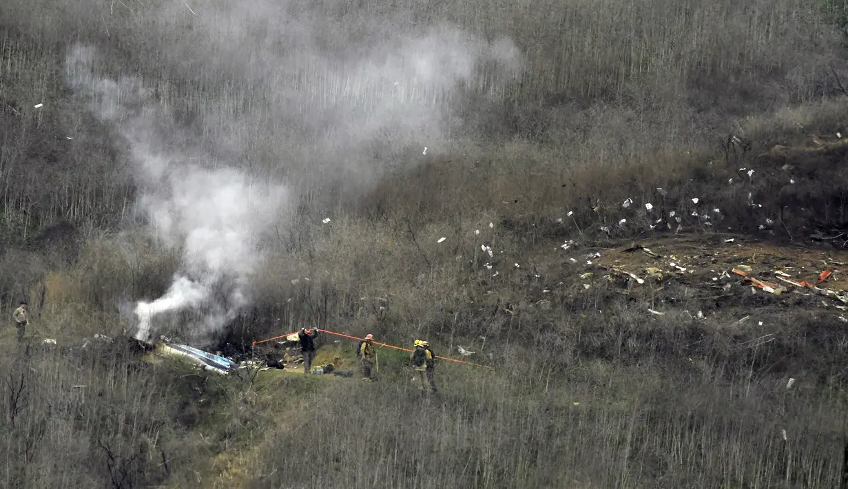 Petugas pemadam kebakaran berusaha memadamkan api di lokasi kecelakaan helikopter yang ditumpangi pebasket NBA Kobe Bryant di sisi bukit di Calabasas, California (26/1/2020). Selain Bryant, empat orang lainnya dalam helikopter itu juga dinyatakan meninggal dunia. (AP Photo/Mark J. Terrill)