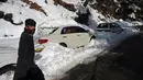 Seorang pria berjalan melewati kendaraan yang terjebak salju di sepanjang jalan Bukit Murree, Pakistan, 9 Januari 2022. Sebanyak 22 wisatawan tewas saat sekitar 1.000 kendaraan terjebak salju tebal di Bukit Murree. (Aamir QURESHI/AFP)