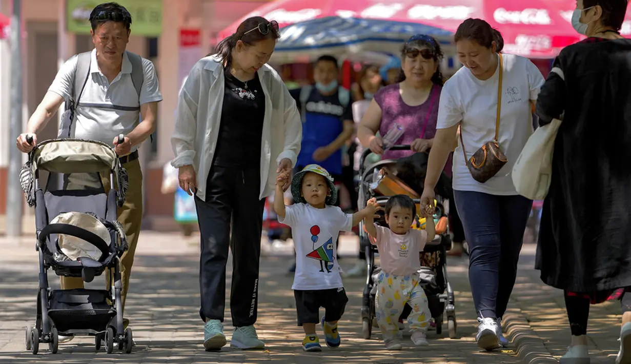 Orang-orang membawa anak-anak mereka ke taman umum selama Hari Anak Internasional di Beijing, China, Selasa (1/6/2021). Para pemimpin China telah mengumumkan akan membiarkan semua pasangan memiliki tiga anak, bukan dua, berharap untuk melawan penuaan cepat masyarakat China. (AP Photo/Andy Wong)