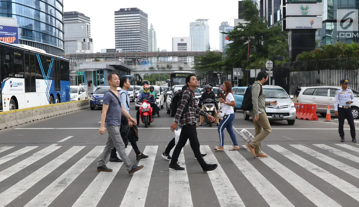 Warga menyebrang jalan Sudirman di kawasan Tosari, Jakarta, Jumat (14/12). Penggunaan pelican crossing di kawasan ini menggantikan fungsi Jembatan Penyebrangan Orang (JPO) Tosari yang akan dibongkar. (Liputan6.com/Helmi Fithriansyah)