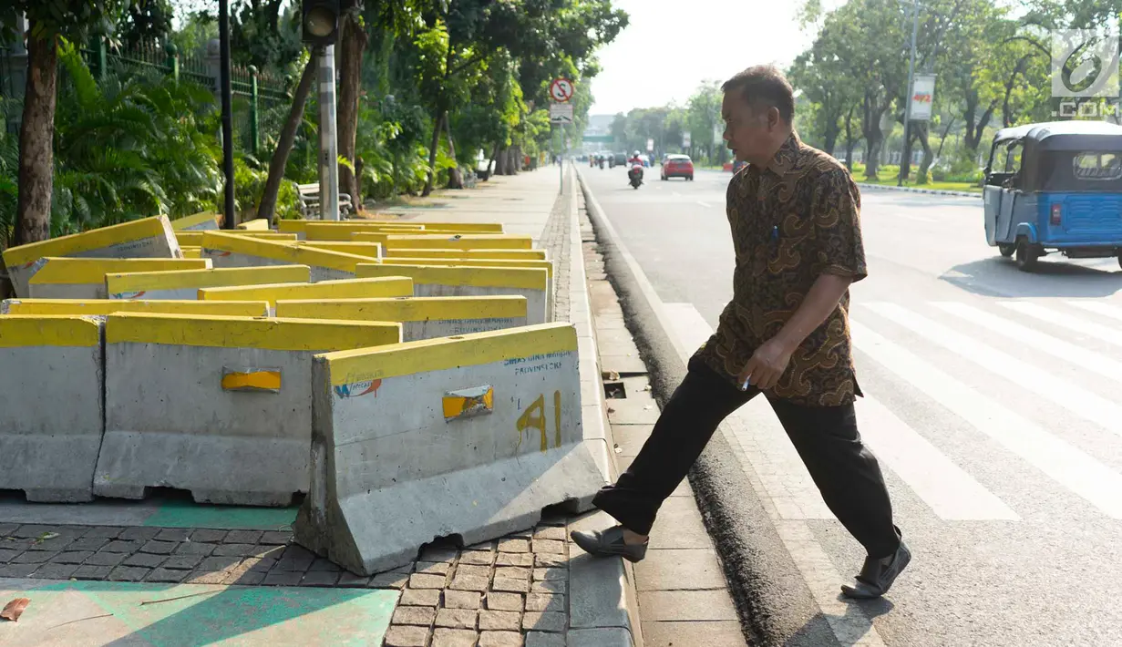Pejalan kaki menghindari pembatas jalan yang menutupi trotoar di Jalan Medan Merdeka Utara, Jakarta, Rabu (3/7/2019). Pembatas jalan yang berada tidak pada tempatnya tersebut mengganggu pejalan kaki karena menutupi badan trotoar. (Liputan6.com/Immanuel Antonius)