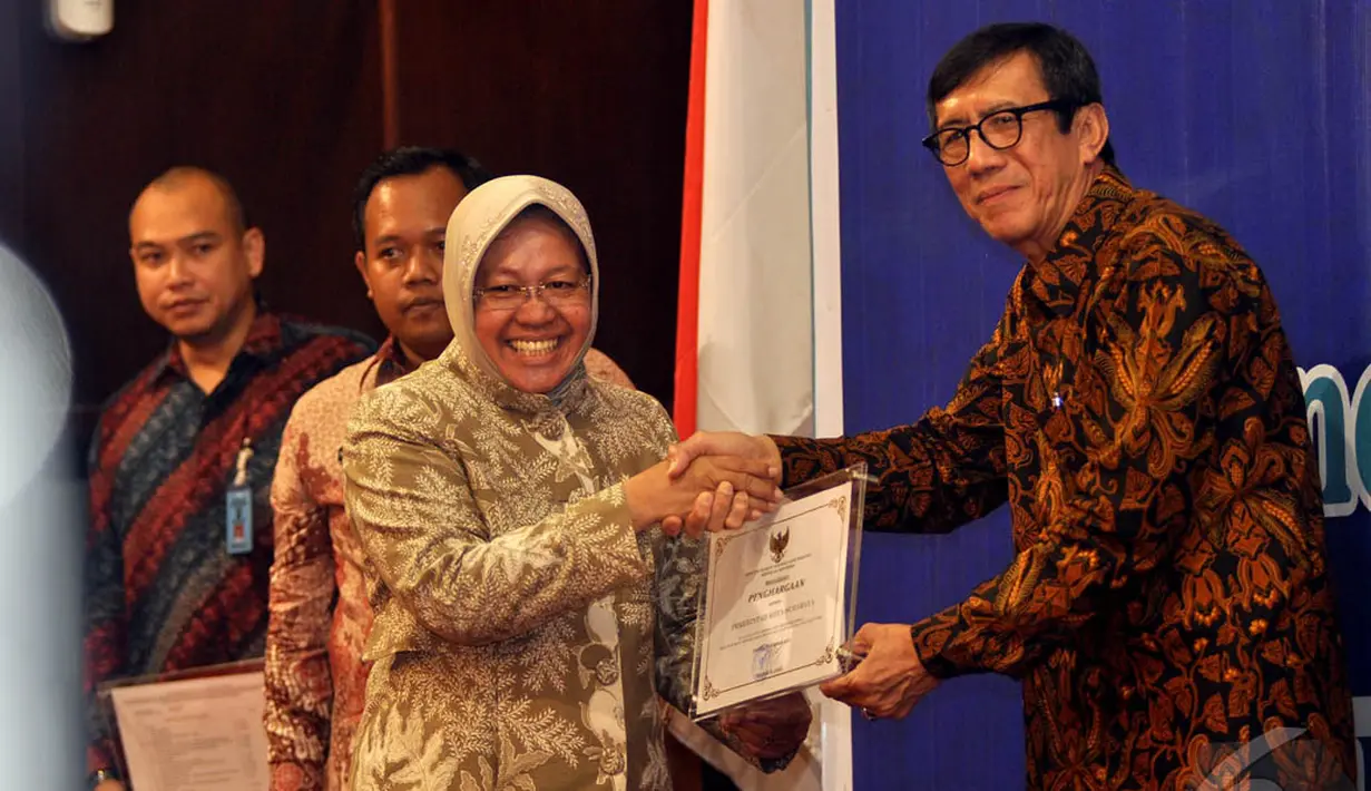 Walikota Surabaya, Tri Rismaharini (kiri) saat menerima penghargaan dari Menkum HAM Yasonna Laoly, Jakarta, Rabu (10/12/2014). (Liputan6.com/Miftahul Hayat) 
