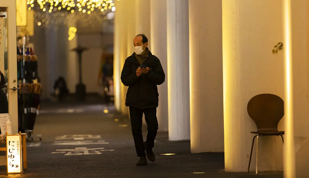 Seorang pria yang mengenakan masker untuk membantu mengekang penyebaran COVID-19 berjalan di Tokyo, Jepang, Kamis (4/2/2021). Tokyo mengonfirmasi lebih dari 730 kasus baru COVID-19 pada 4 Februari 2021. (AP Photo/Hiro Komae)