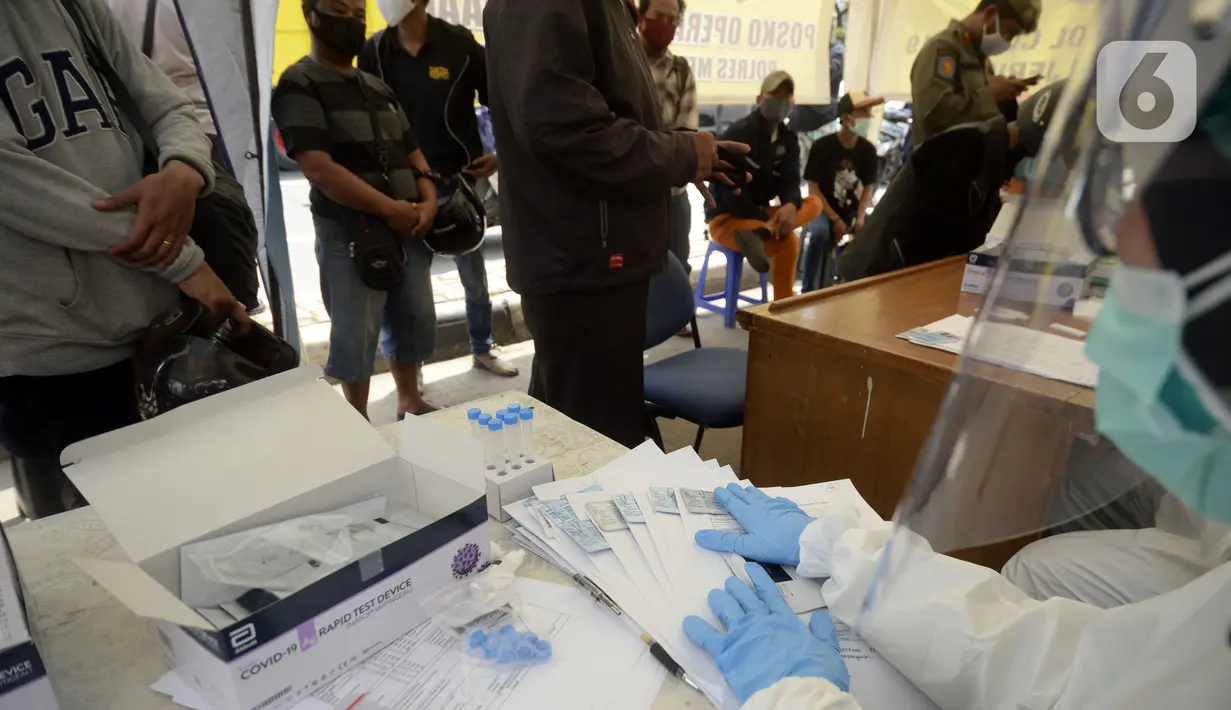 Petugas medis bersiap melakukan rapid test pada pengendara yang terjaring razia masker di Jalan Panjang, Kedoya, Jakarta Barat, Senin (2812/2020). Pengendara yang tidak mengenakan masker langsung menjalani rapid test antigen gratis untuk mencegah penularan COVID-19. (merdeka.com/Dwi Narwoko)