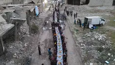 Pemandangan udara menunjukkan warga Suriah duduk di tengah-tengah bangunan yang rusak untuk berbuka puasa di Tadef, dekat kota perbatasan al-Bab, yang dikendalikan oleh pemberontak yang didukung Turki di Suriah di pedesaan timur provinsi Aleppo (18/4/2022). (AFP/Bakr Alkasem)