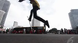 Seorang remaja mencoba trik lompat dengan skateboard di kawasan Bundaran HI Jakarta, Minggu (14/12/2015). (Liputan6.com/Faizal Fanani)
